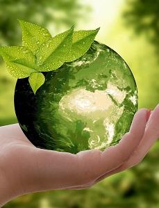 Hand holds a drop of water that represents the earth with on top green leaves