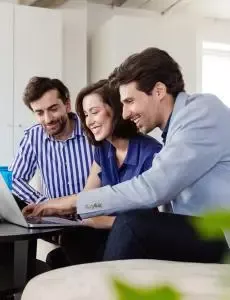 three colleagues looking at a laptop together