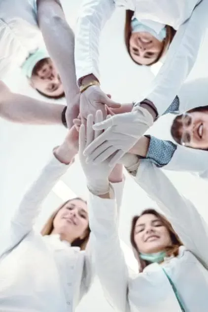 Five people joining hands in a huddle.